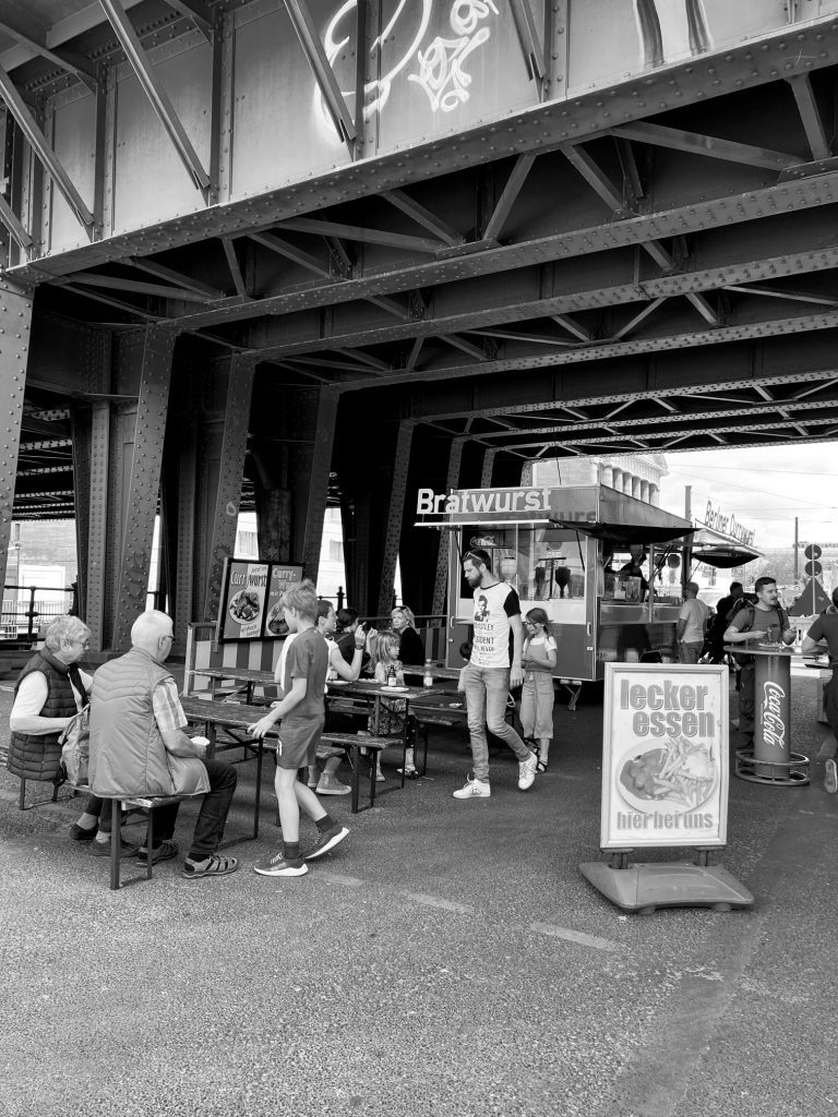 Street photography in Berlin. Photo of a people eating bratwurst in a street. Black and white photo. 