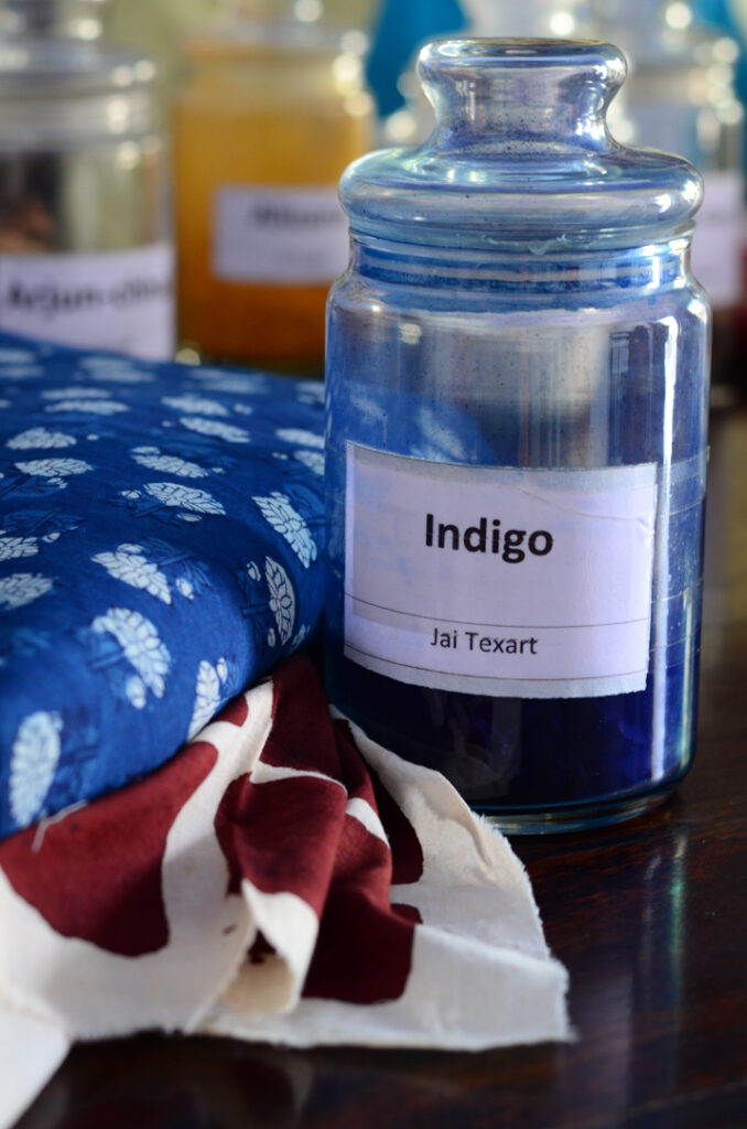 A jar of indigo dye from Jai Texart sits beside beautifully printed fabrics on a workshop table in Bagru. Photo Lizane Louw (Bagru, 2016)