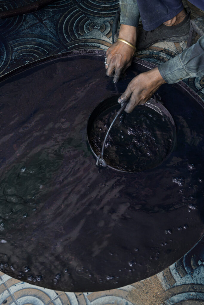 An artisan's hands skillfully stir a vat of indigo dye, one of the essential steps in India's Dabu print printing process. Photo Lizane Louw